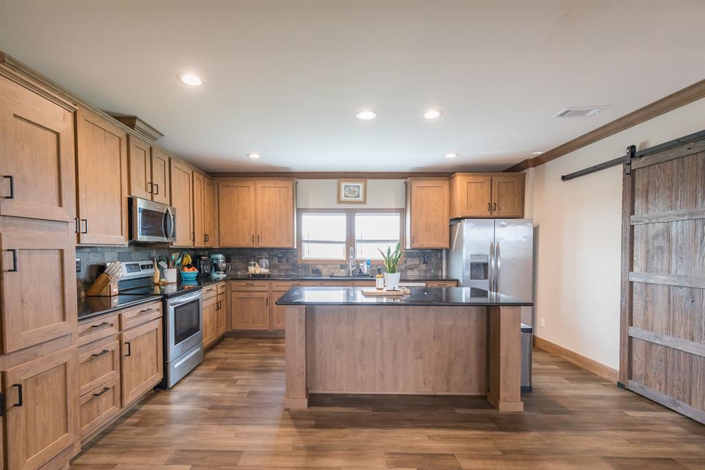 10099 County Road 452 Merkel, TX 79536 - Photo 2 of 28 a kitchen with stainless steel appliances granite countertop a refrigerator a sink dishwasher a stove and white countertops with wooden floor