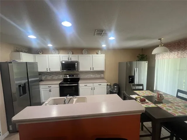 a kitchen with a sink a stove a refrigerator and chairs