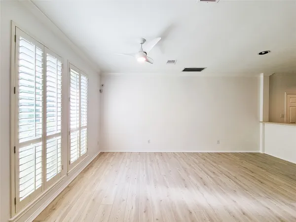 an empty room with wooden floor fan and windows