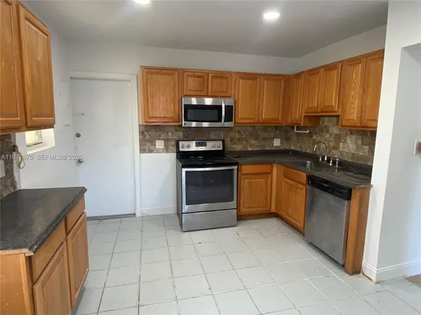 a kitchen with stainless steel appliances granite countertop a stove a sink and a microwave
