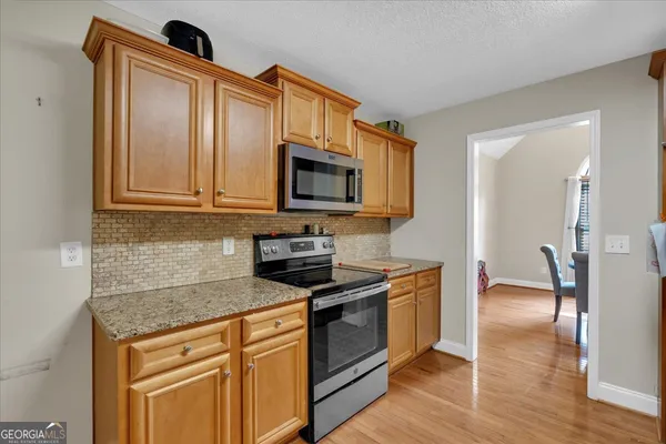 a kitchen with stainless steel appliances granite countertop a stove a sink and a microwave