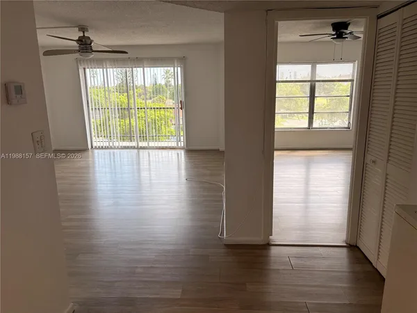a view of an empty room with wooden floor and a window