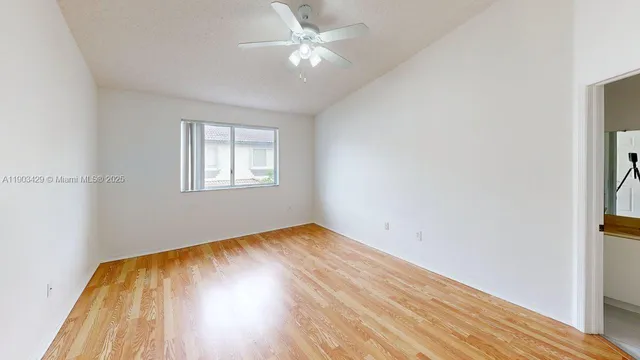 an empty room with wooden floor closet and windows