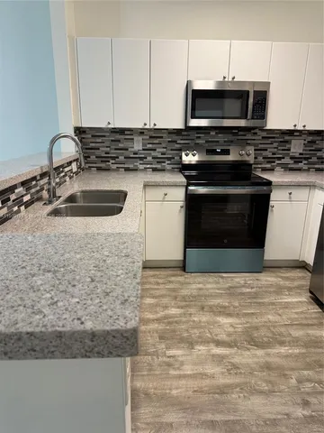 a kitchen with stainless steel appliances granite countertop a stove a sink and a microwave