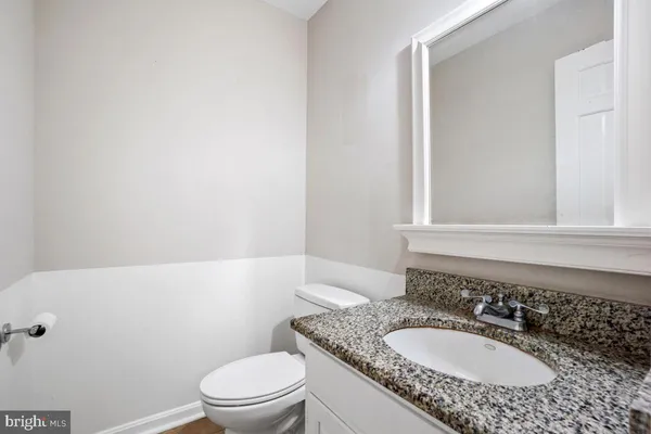 a bathroom with a granite countertop sink a mirror and a toilet