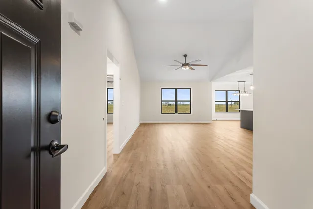 an empty room with wooden floor ceiling fan and windows