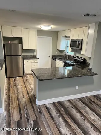 a kitchen with granite countertop a refrigerator and microwave