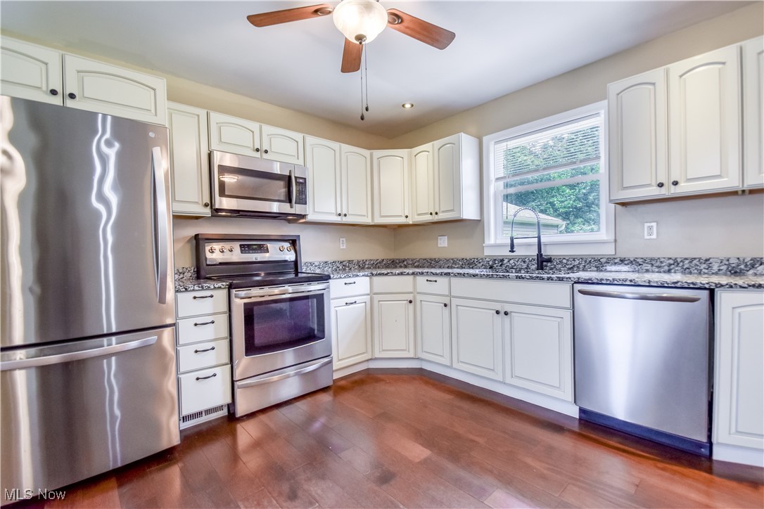 1919 Sandgate Road Madison, OH 44057 - Photo 7 of 28 Kitchen featuring stainless steel appliances, stone counters, ceiling fan, dark wood-style floors, and white cabinets