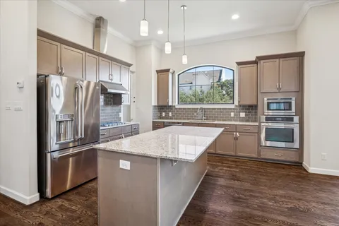 a kitchen with stainless steel appliances granite countertop a refrigerator a sink and a stove