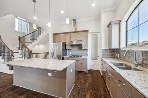 a kitchen with stainless steel appliances granite countertop a sink a stove and a refrigerator