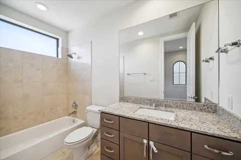 a bathroom with a granite countertop toilet a sink and a bathtub