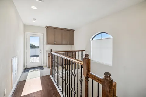 a view of a hallway to a livingroom with wooden floor and stairs