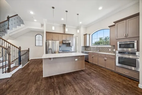 a kitchen with stainless steel appliances granite countertop a kitchen island hardwood floor sink and stove