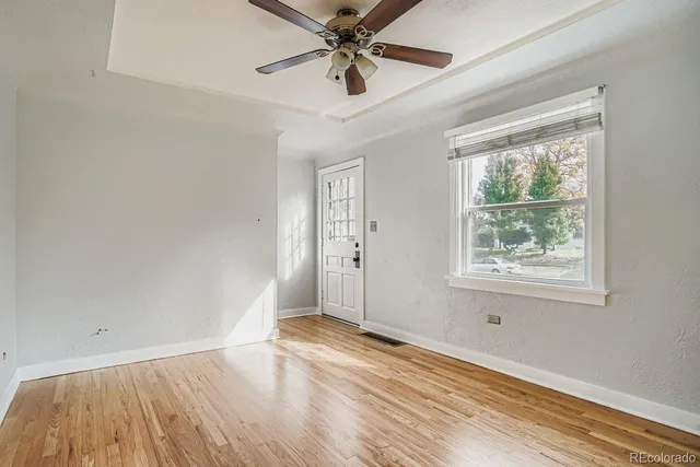 a view of an empty room with a window and wooden floor