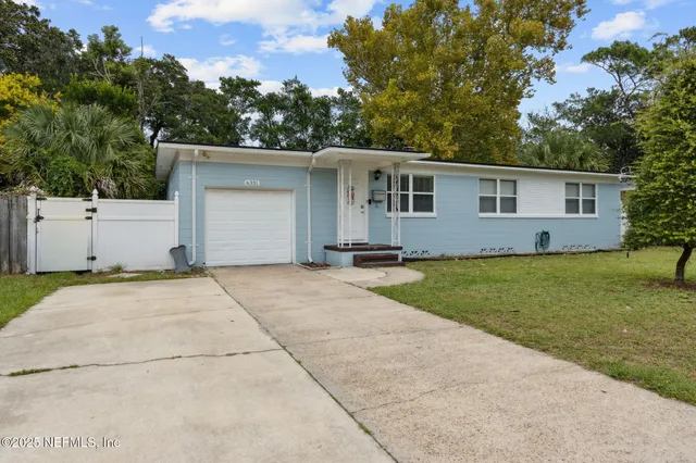 a front view of house with yard and trees in the background