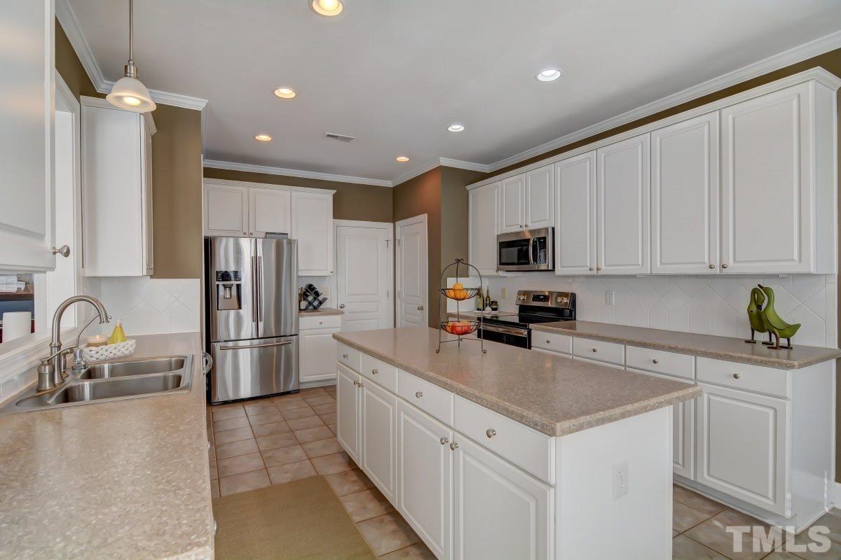 3902 Sunset Maple Court Raleigh, NC 27612 - Photo 7 of 21 a kitchen with white cabinets and stainless steel appliances