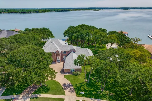 a view of a lake with lawn chairs and large trees