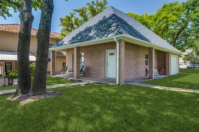 a backyard of a house with table and chairs plants and large tree