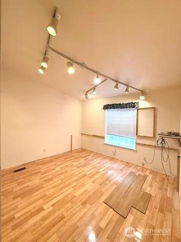 a view of empty room with wooden floor and fan