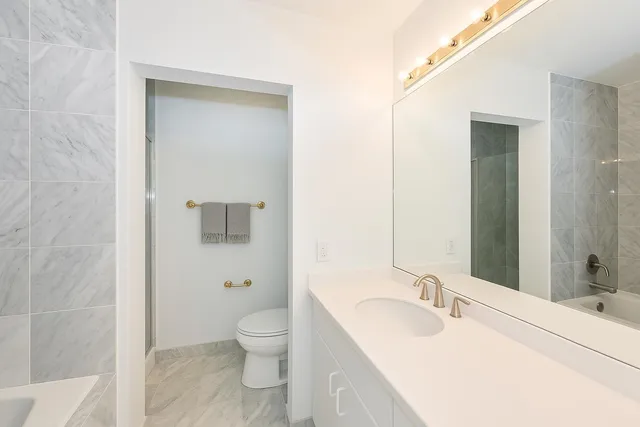 a bathroom with a granite countertop sink a toilet and shower