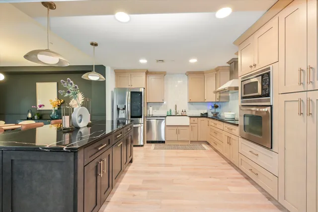 a large kitchen with stainless steel appliances kitchen island granite countertop a large counter top and a stove