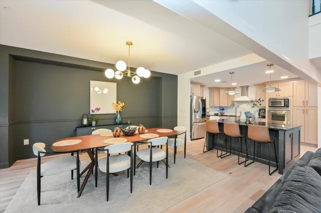 a dining room with wooden floor a chandelier a wooden table and chairs