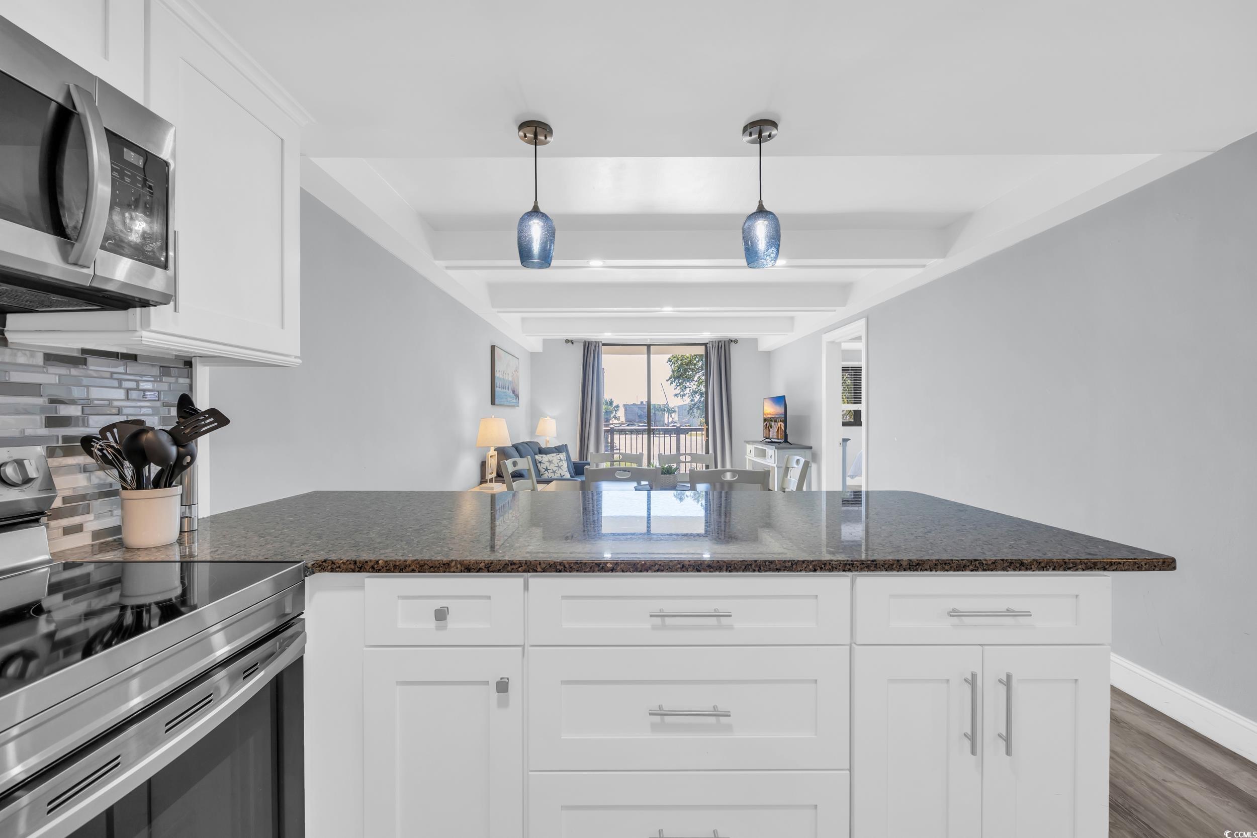 601 Mitchell Drive, Unit 203 Myrtle Beach, SC 29577 - Photo 12 of 40 Kitchen featuring stainless steel appliances, a peninsula, white cabinetry, dark wood-style flooring, and hanging light fixtures