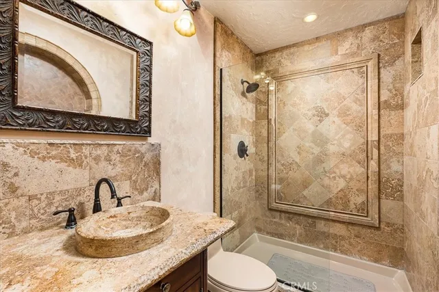 a bathroom with a granite countertop sink toilet and shower