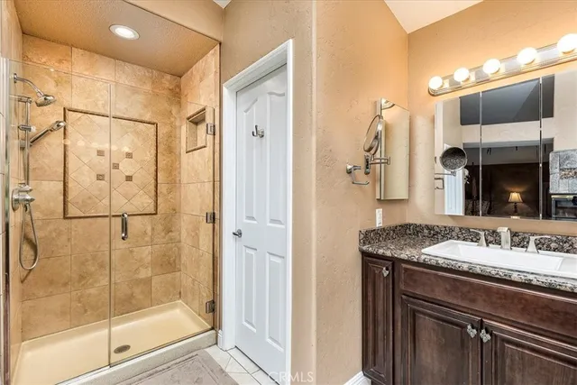a bathroom with a granite countertop sink a mirror and shower
