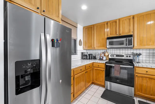 a kitchen with stainless steel appliances granite countertop a refrigerator and a stove top oven