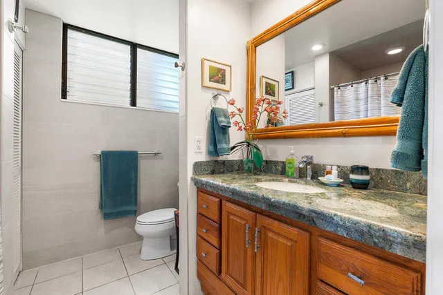 a bathroom with a granite countertop sink a toilet and a large mirror