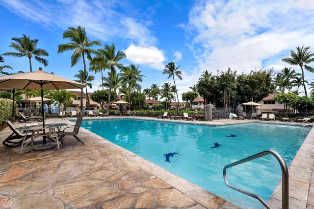 a view of a swimming pool with a table and chairs under an umbrella