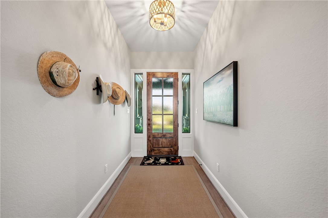 30163 High Spirit Ranch Road Hempstead, TX 77445 - Photo 7 of 49 Doorway to outside featuring wood finished floors and a chandelier