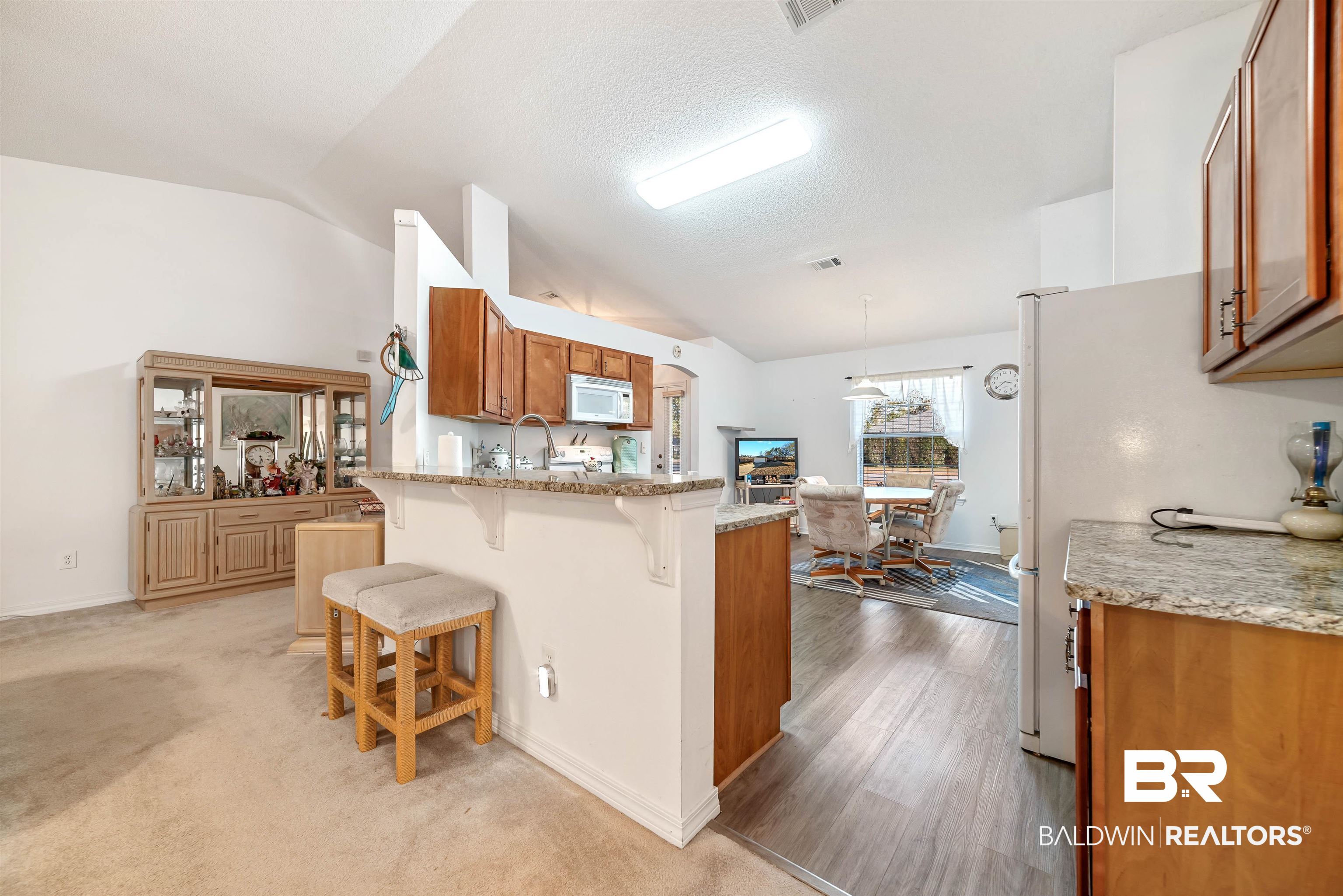 1 Bay Circle Foley, AL 36535 - Photo 4 of 28 Kitchen featuring granite countertops, kitchen peninsula, vaulted ceiling and breakfast area