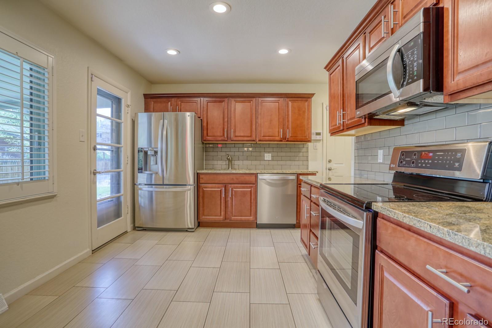 1465 South Vancouver Court Lakewood, CO 80228 - Photo 10 of 31 a kitchen with stainless steel appliances granite countertop a stove a sink and a refrigerator