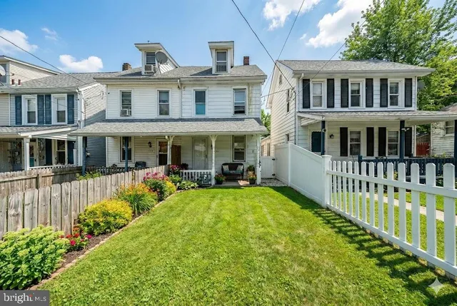 a view of a house with a small yard and wooden fence