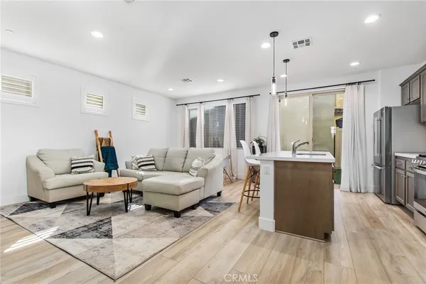 a kitchen with stainless steel appliances granite countertop a refrigerator a sink dishwasher a stove and a dining table with wooden floor