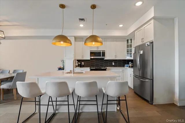 a kitchen with stainless steel appliances a table chairs and a refrigerator