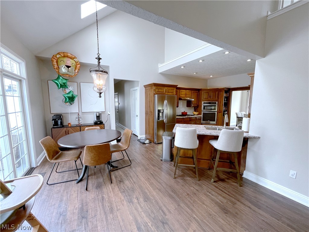 718 Sunridge Road Fairlawn, OH 44333 - Photo 8 of 49 Kitchen featuring pendant lighting, stainless steel appliances, high vaulted ceiling, a kitchen bar, and light wood-type flooring