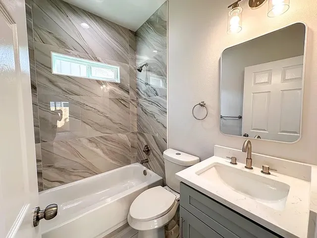 a bathroom with a toilet a sink a mirror a bathtub and shower