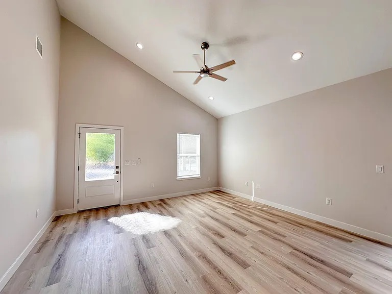 817 5th Street Lockhart, TX 78644 - Photo 2 of 18 an empty room with wooden floor ceiling fan and windows