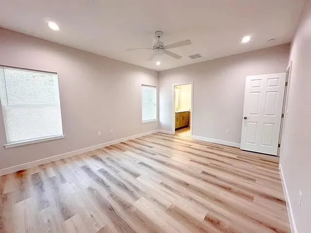 an empty room with wooden floor cabinet and windows