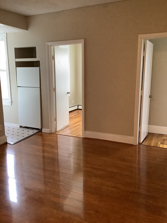 61 Vine Street, Unit 35 Lynn, MA 01905 - Photo 4 of 11 an empty room with wooden floor and a refrigerator