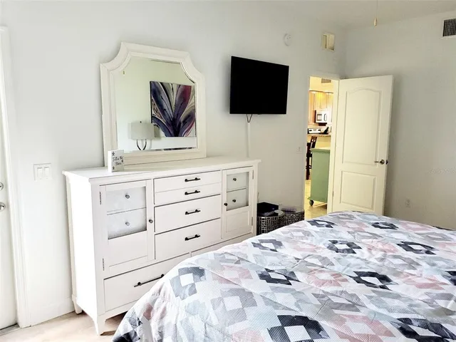 a bedroom with a bed a flat screen tv and a dresser