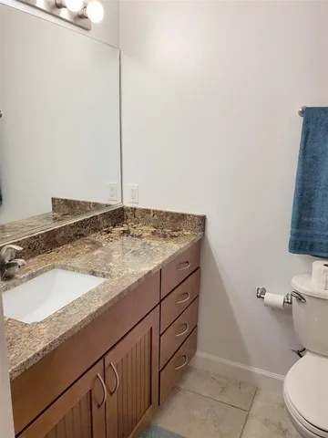 a bathroom with a granite countertop sink and a toilet