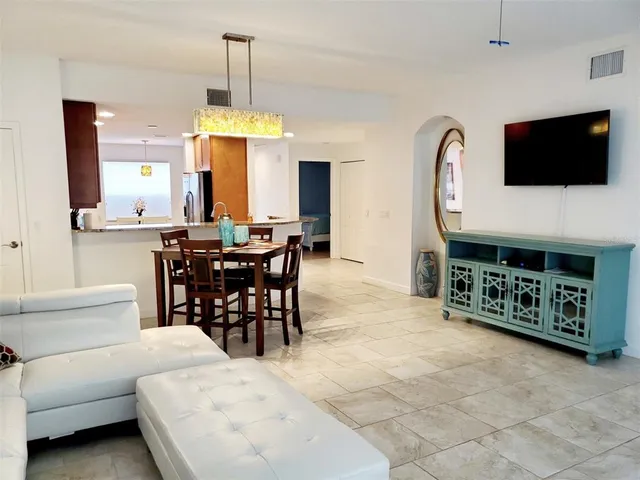 a living room with furniture a flat screen tv and kitchen view