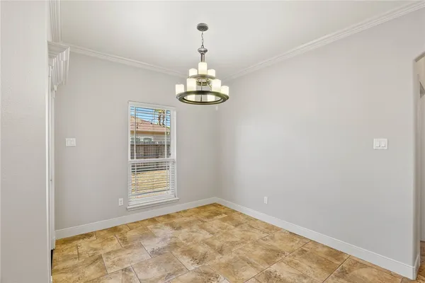 an empty room with chandelier fan and windows