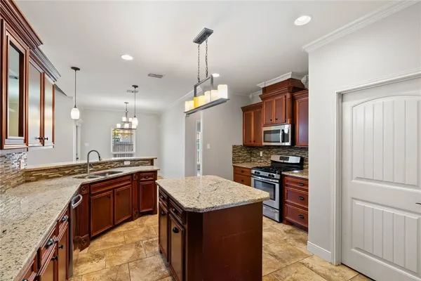 a kitchen with granite countertop kitchen island stainless steel appliances a sink stove and refrigerator