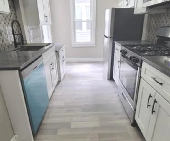 a kitchen with granite countertop a sink stove and refrigerator
