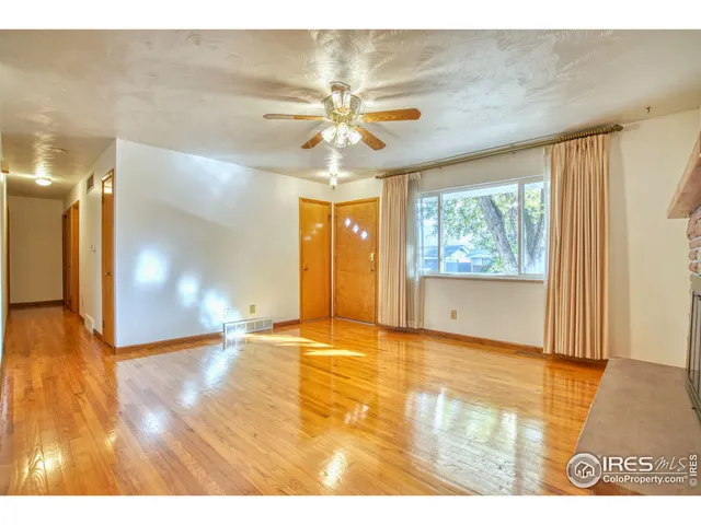a view of an empty room with window and wooden floor